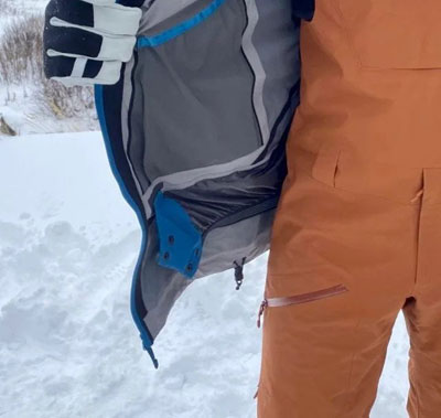 A skier wearing a snow jacket showing the powder skirt. 